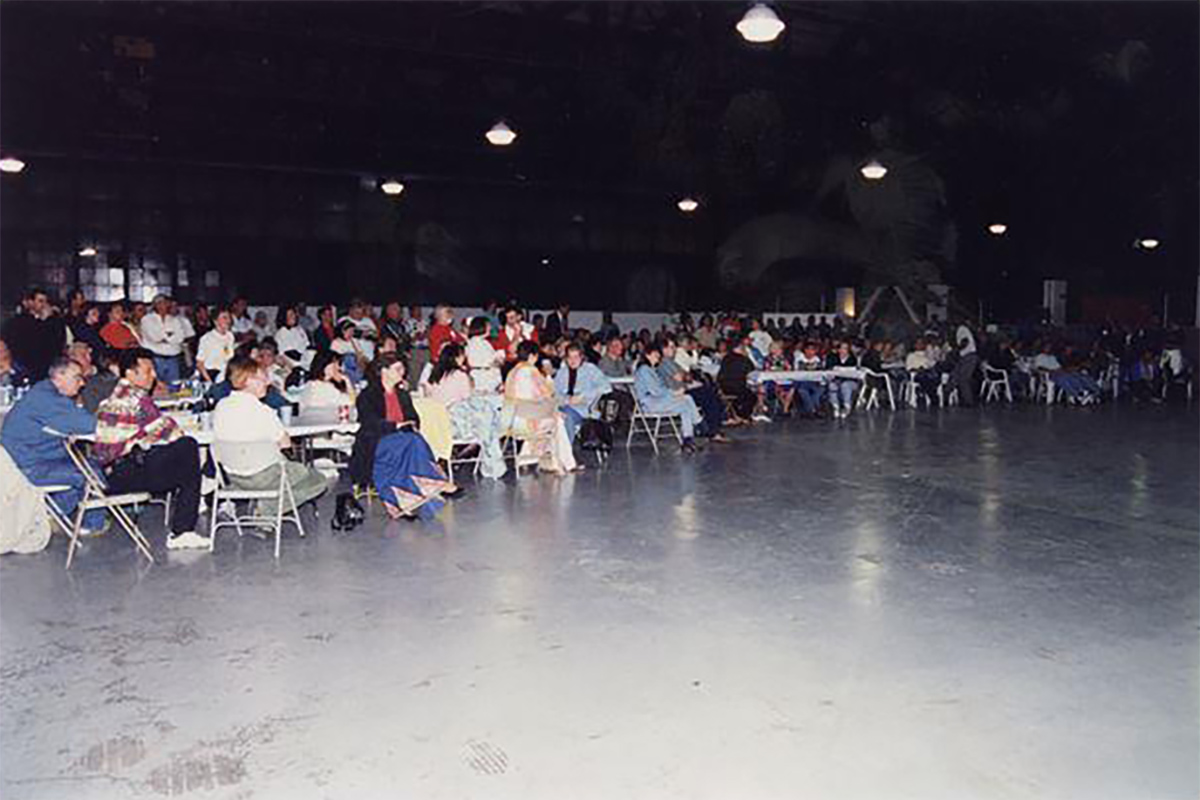 Kosovar refugees sitting in a large airplane hangar.