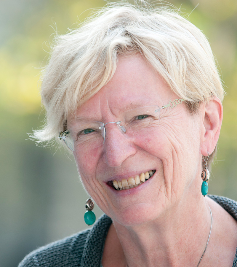 A woman with short hair and glasses smiles for the camera.