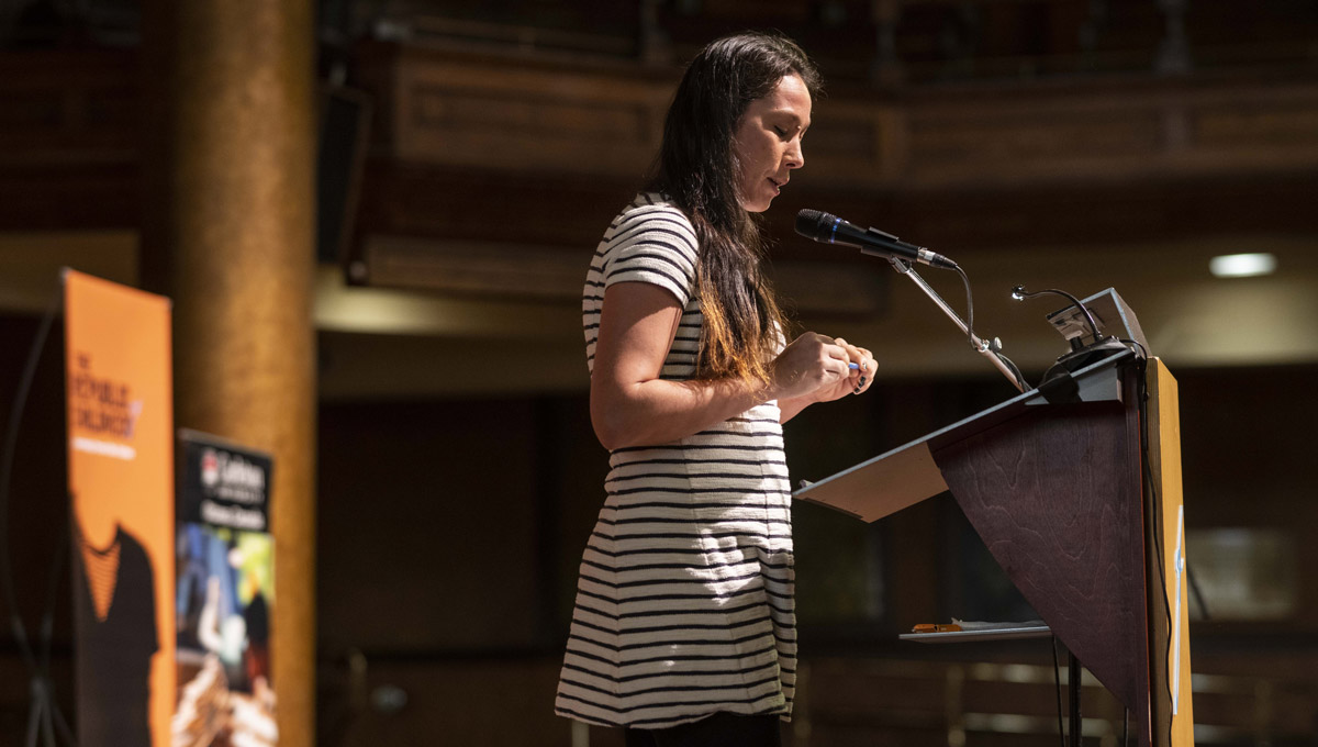 A youth in a striped dress speaks at a podium in the sanctuary of the Dominion-Chalmers United Church.