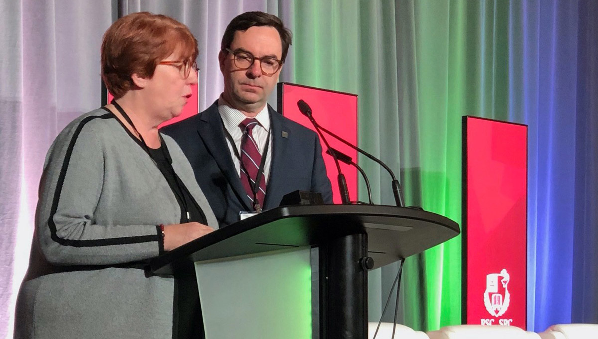 FASS Dean Pauline Rankin and a man in a suit speak at the podium during the Royal Society Celebration.