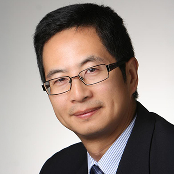 A professional headshot of a man with glasses wearing a suit and tie.