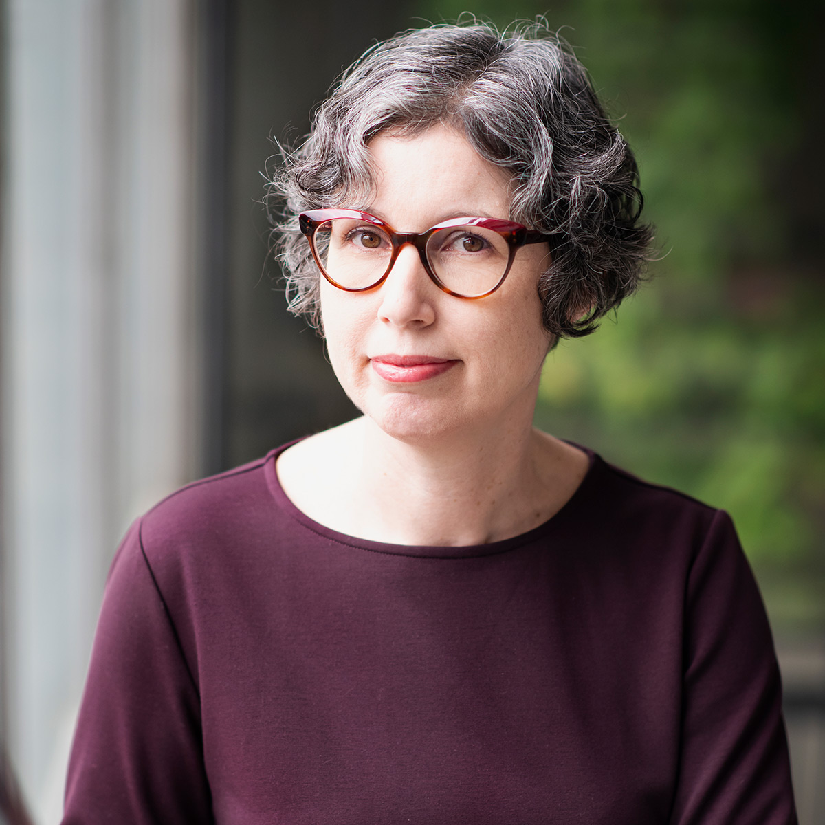 A woman with short hair wearing glasses poses for a photo.