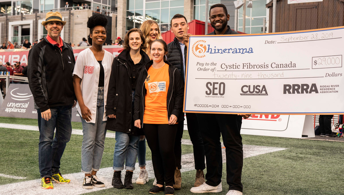 Ravens hold up an oversized cheque on the field at a Redblacks game.