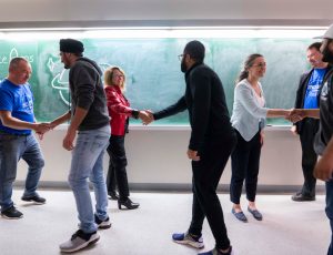 Carleton and Ottawa-area students shake hands near a blackboard during Space Apps Ottawa 2019.