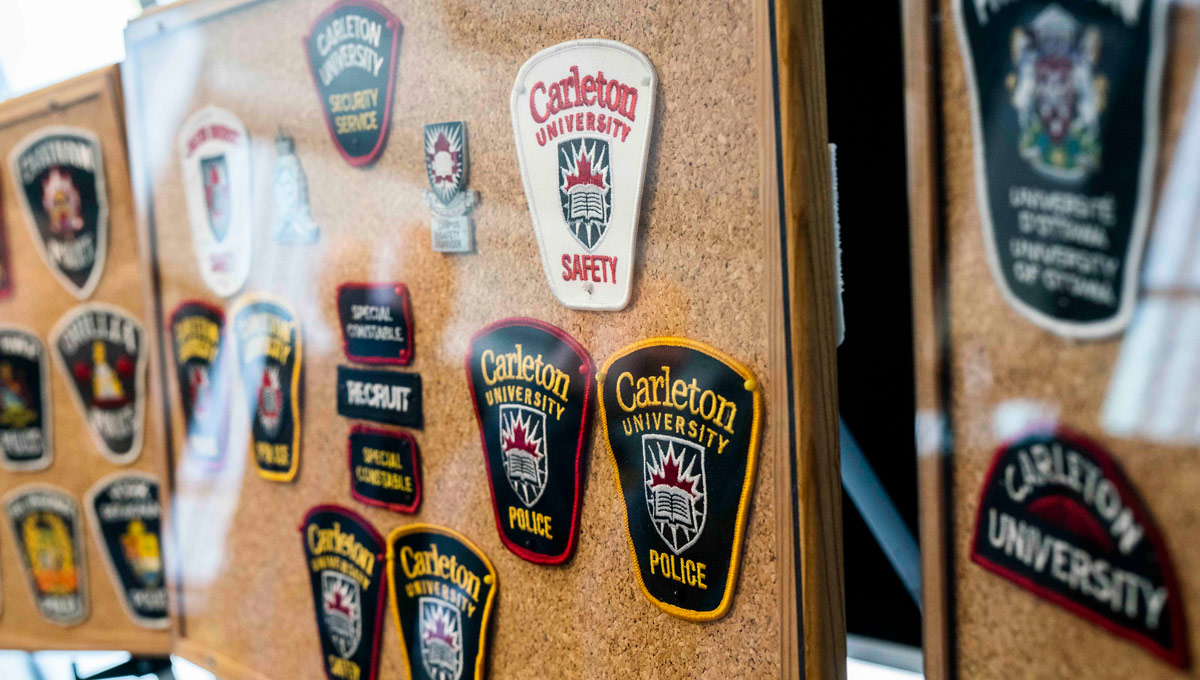 Various University Safety badges on display. An Ottawa police representative speaks at a podium. Carleton's special constables marked their 25th anniversary in Oct. 2018 with a celebration that recognized its partnership with the Ottawa Police Service.