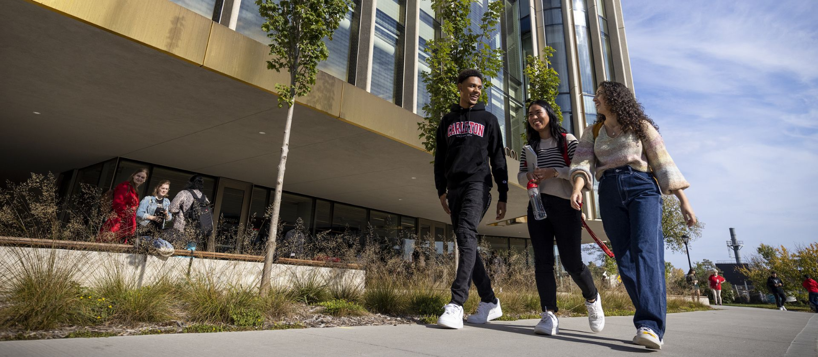 three students walking past a building on Carleton's campus