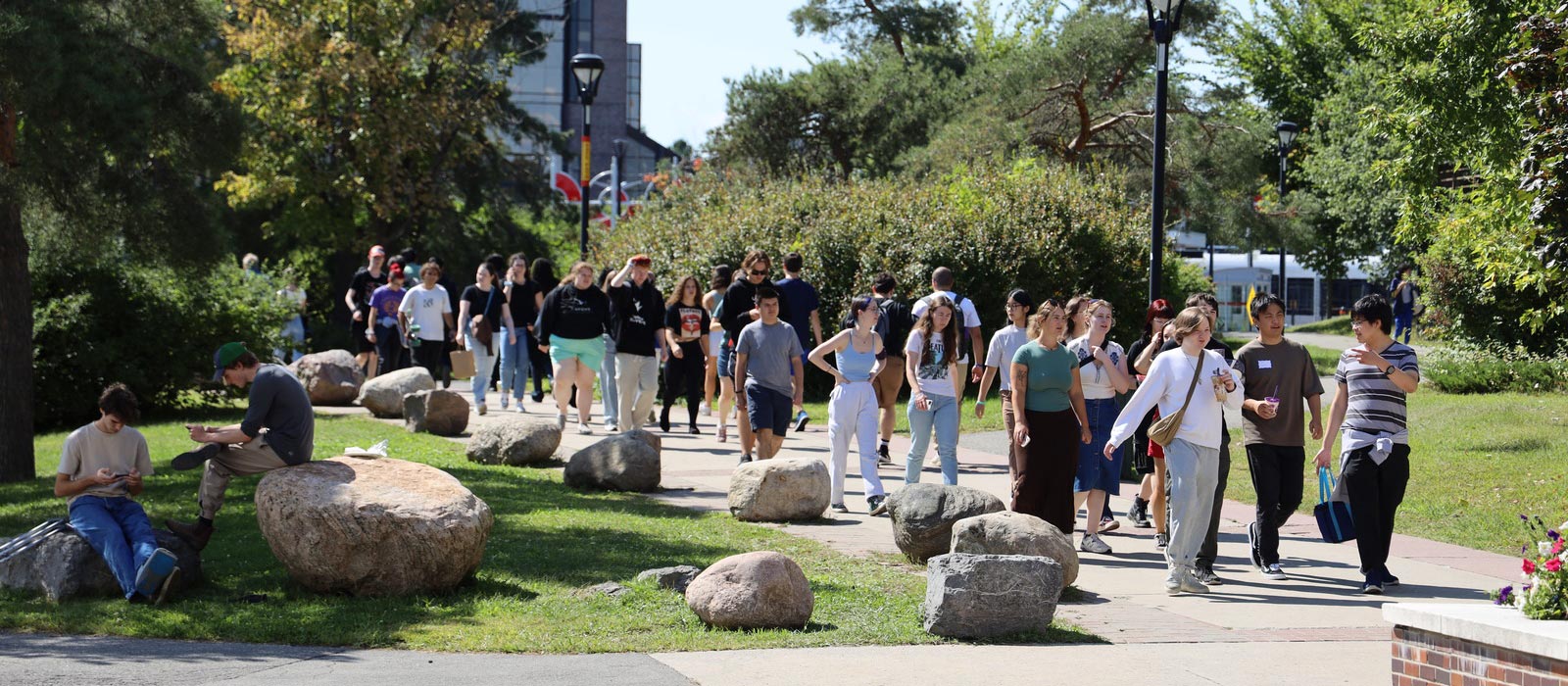 A large group of young adults walking down a path outside.