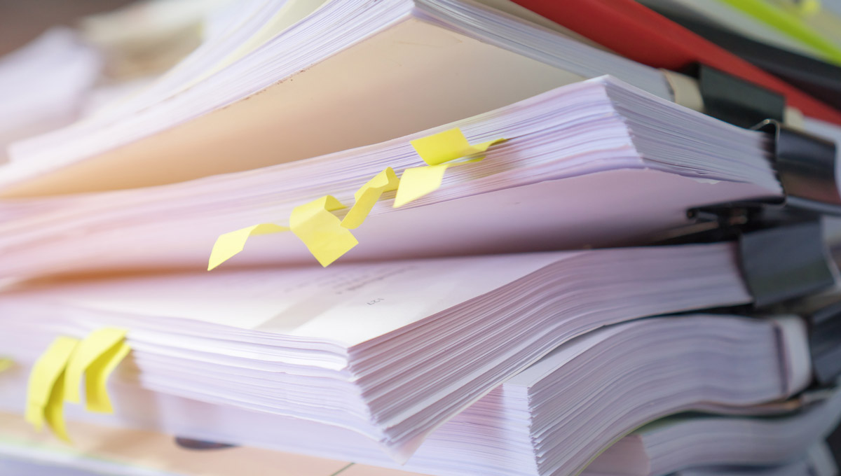 Dog-eared paper surveys sit on a desk.