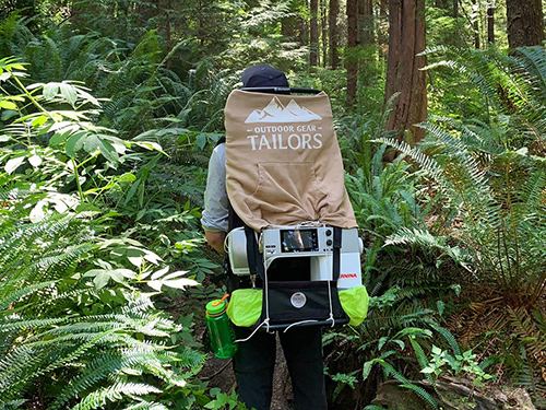 A person walks through a forest wearing a sustainable bag