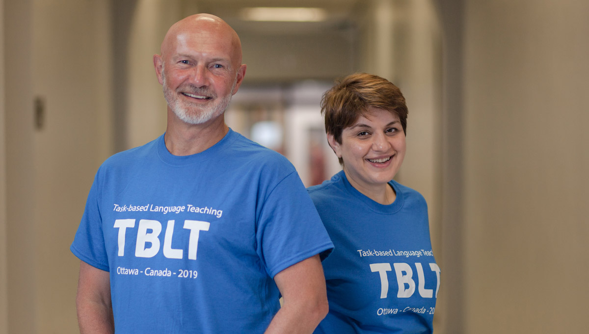 Profs. David Wood and Eva Kartchava pose in T-shirts emblazoned with the Conference on Task-Based Language Teaching conference wordmark.