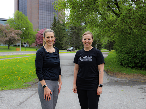 Two runners posing for a photo on a bike path.