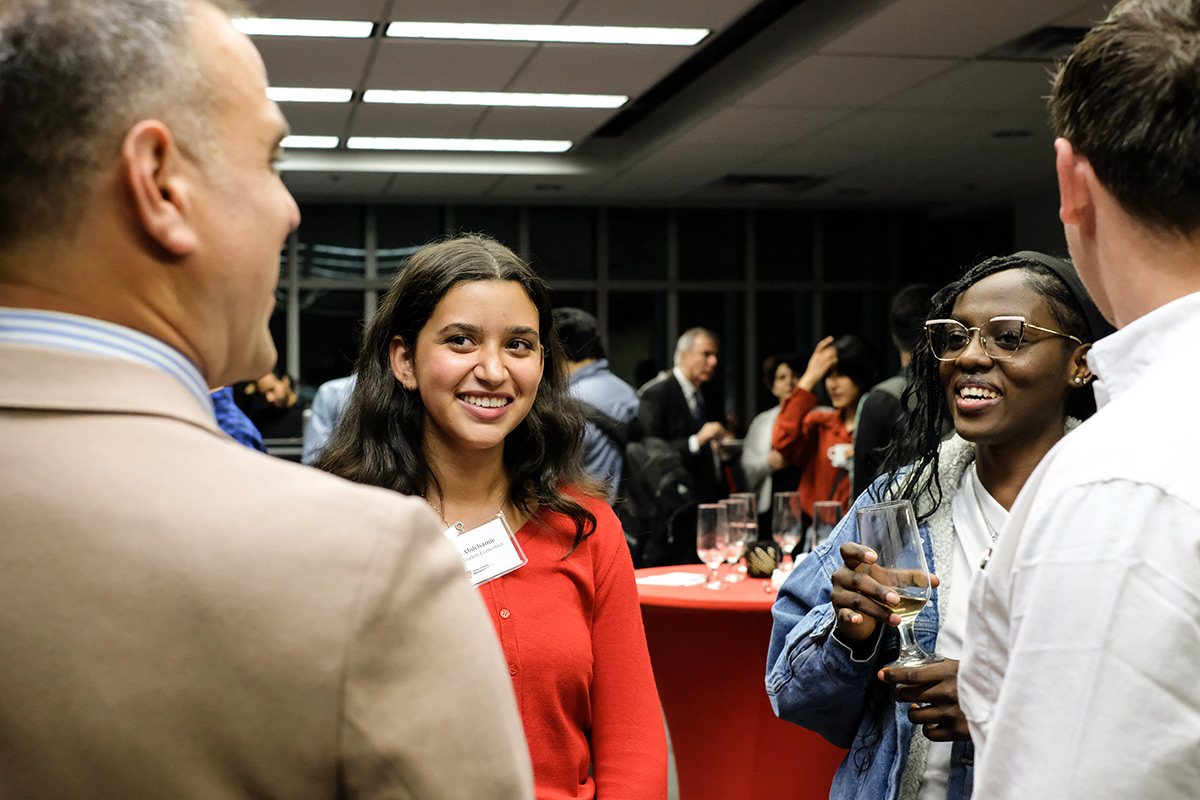 A small group of people standing in a circle and having a discussion at an event.