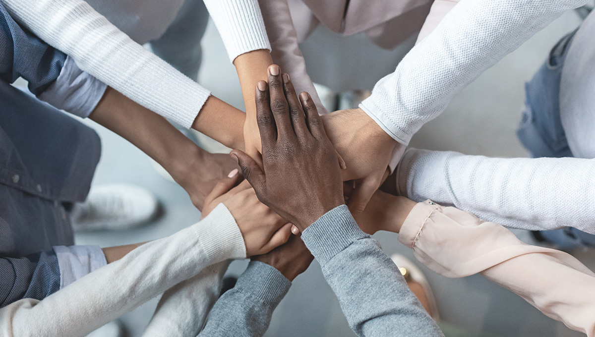 Top view of international business team showing cooperation with putting their hands together on top of each other