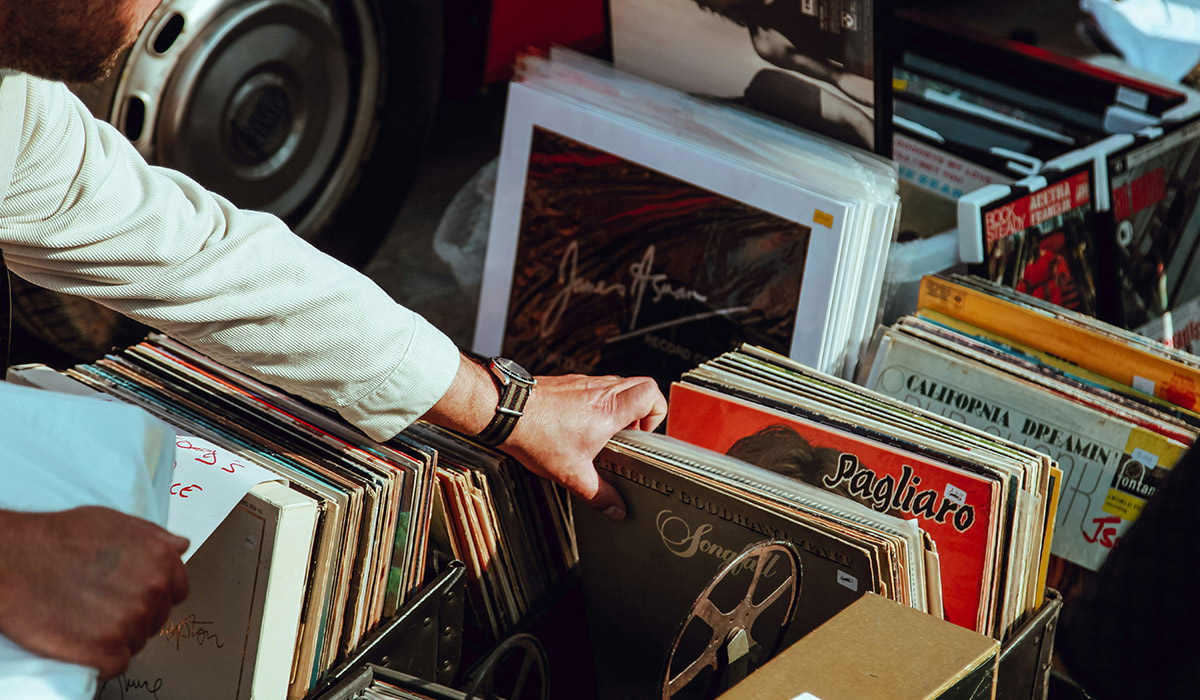 A man wearing a wristwatch digs through a vinyl record crate.