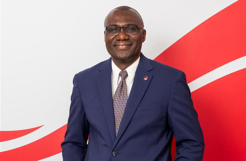 A professional headshot of a man in glasses wearing a suit.