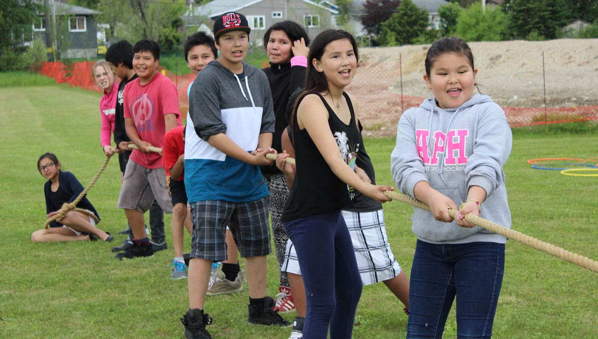 Indigenous Communities: Children and youth play tug of war outdoors.